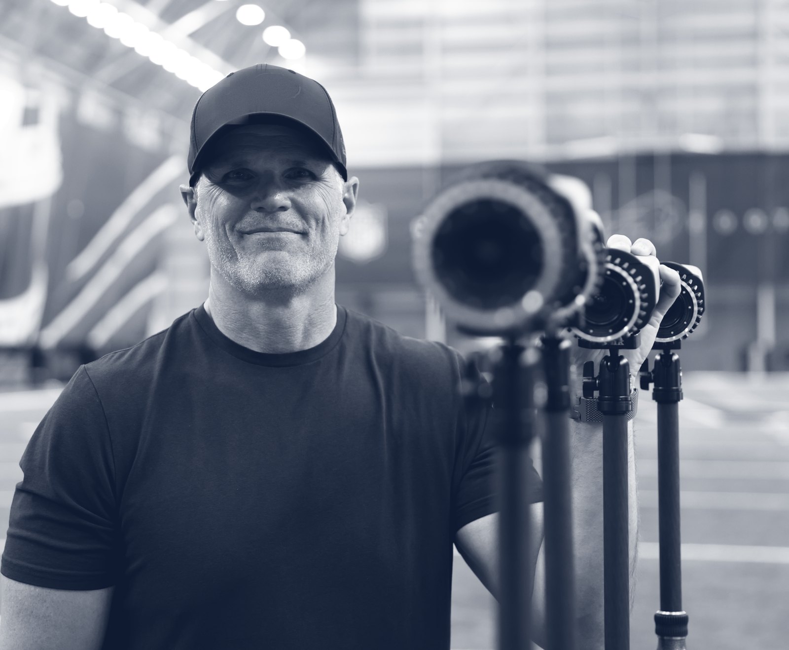 Chris Hess beside the mobile lab's motion-capture cameras on an indoor practice field.